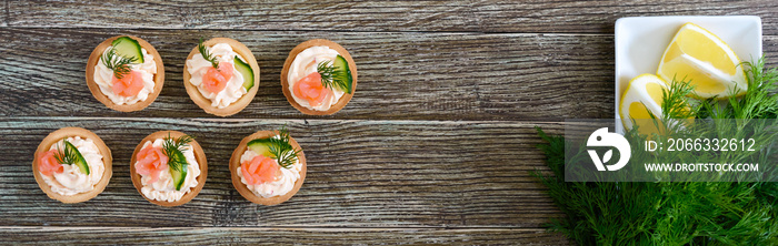 Tartlets with cream cheese and salted salmon on a wooden background. Tasty light snack for a party. Finger Food. The top view. Banner.