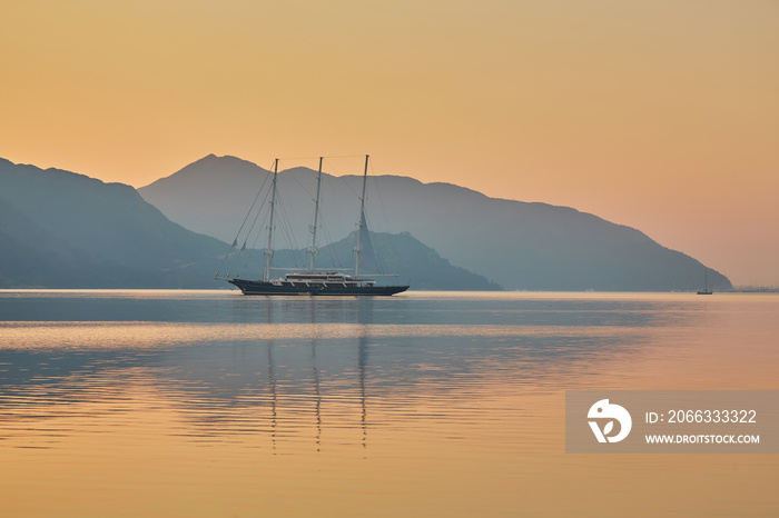 mountain and lonely motor boat reflected sunrise in a calm sea, Marmaris