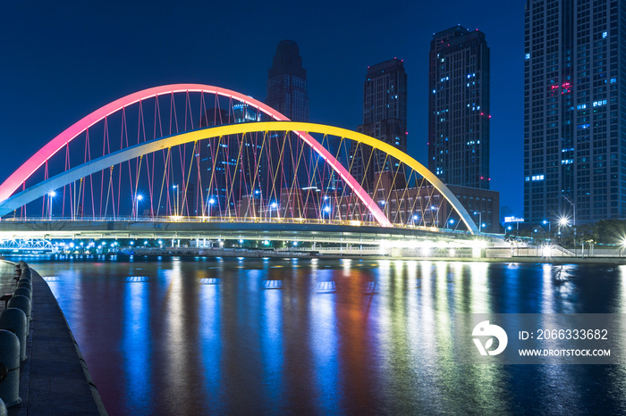 Tianjin Hai river waterfront downtown skyline with illuminated Dagu bridge,China.