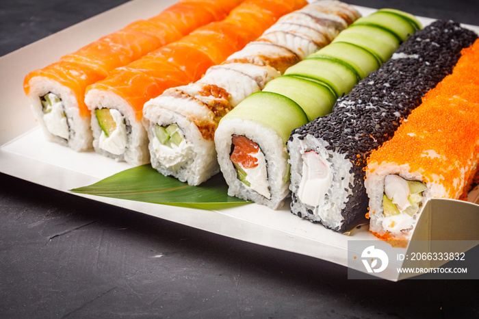 delicious sushi rolls in a delivery box on a black background