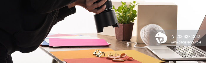 photographer taking photo of composition with flora and accessories for commercial photo shooting with camera and laptop, cropped view