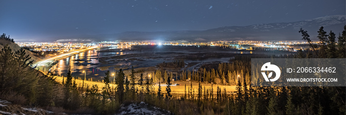 Aerial, panorama shot of Whitehorse city in northern Canada, capital of Yukon Territory. Taken in fall, autumn at night time with bright city lights and sky.