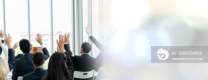 Group of business people meeting in a seminar conference widen view . Audience listening to instructor in employee education training session . Office worker community summit forum with speaker .