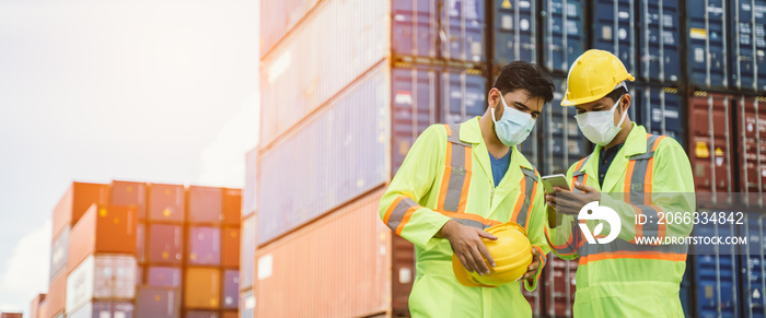 Engineer or worker man wearing surgical mask and safety white head using a laptop to protection for coronavirus in during concern about covid pandemic.Workers wearing protective mask working in cargo.