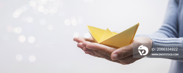 yellow paper boat on hand of woman leader