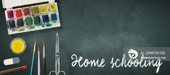 message HOME SCHOOLING with art equipment on a blackboard