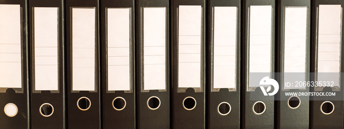 Black office folders standing on cabinet shelves.