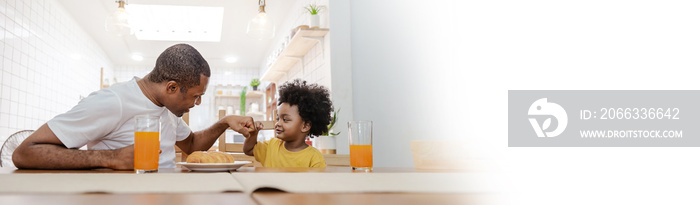 Portrait of happy African american father and son hands fist bump during breakfast time at dining table with copy space. Single dad family love lifestyle, father’s day panoramic banner