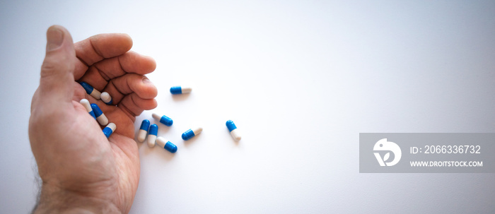 An elderly man’s hand holds pills in the palm of his hand on a white background. Medicines falling out of the hand on a white isolate.