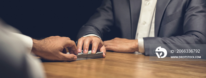 Dishonest businessman secretly giving money to his partner in the dark