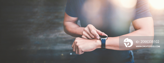 Athletic man using fitness tracker or smart watch between run training outdoors.