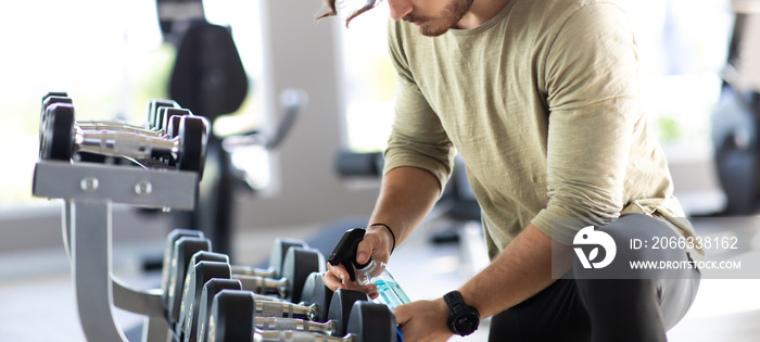 Fitness staff cleaning exercise machines alcohol sanitizer spray at the gym. preventive disease of the Covid 19 virus