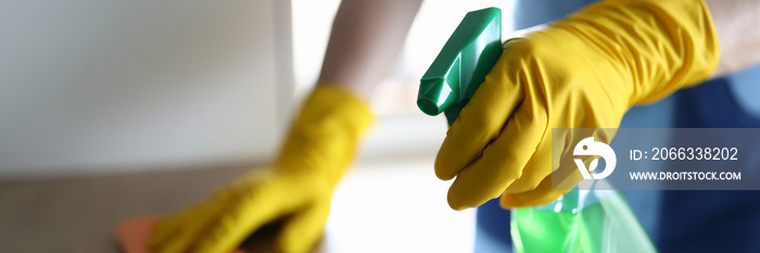 Female hands in gloves disinfect table at home. Thorough cleaning workplace. Hand glove wipes surface table with towel. Apartment and office cleaning. Pandemic housing disinfection