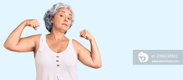 Senior woman with gray hair wearing casual clothes showing arms muscles smiling proud. fitness concept.