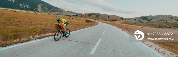 Full length portrait of an active triathlete in sportswear and with a protective helmet riding a bicycle. Selective focus