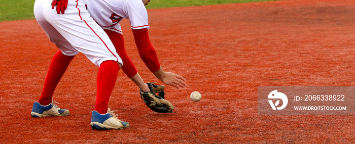 Baseball infielder fielding the ball on a red turf field