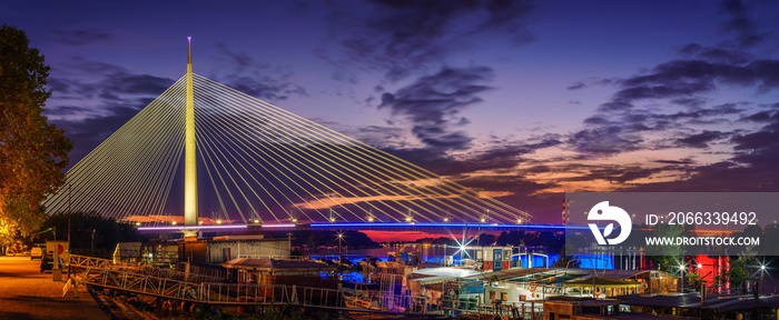 Belgrade panorama Ada bridge Sava River by night, boats and colorful reflection on water