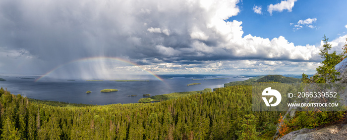 panorama view of Pielina Lake and islands in Koli National Park in Finland with a rainbow under an expressive cloudy sky