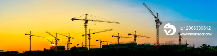 Tower crane and building construction site silhouette at sunrise.panoramic view.