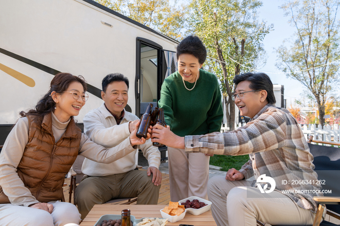 一群中老年人坐在房车露营地喝啤酒聊天