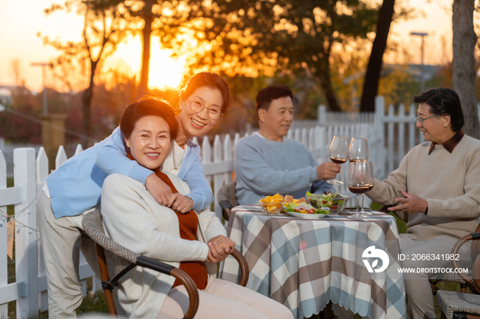 夕阳下中老年朋友在庭院里聚会喝酒聊天