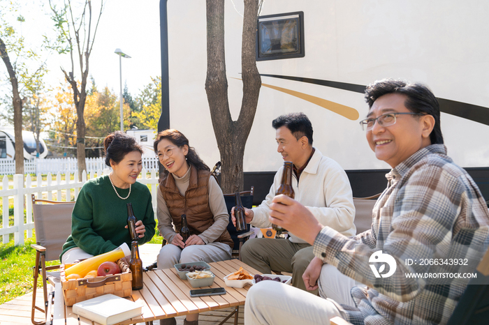 一群中老年人坐在房车露营地喝啤酒聊天