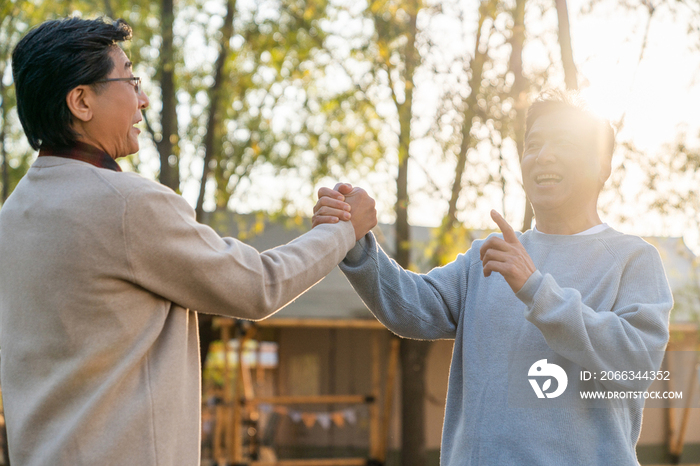 两个中老年男人开心地握手