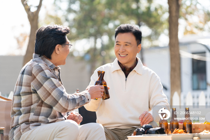 两个老年男人坐在露营地喝啤酒