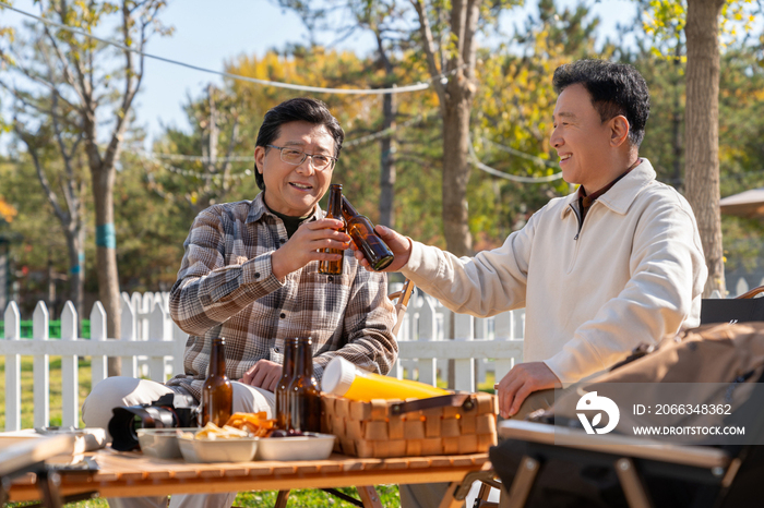 两个老年男人坐在露营地喝啤酒