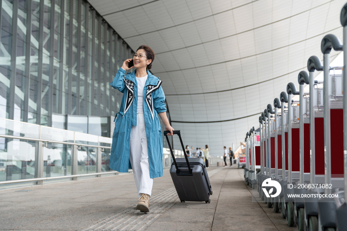 老年女人在机场拉着行李箱打电话