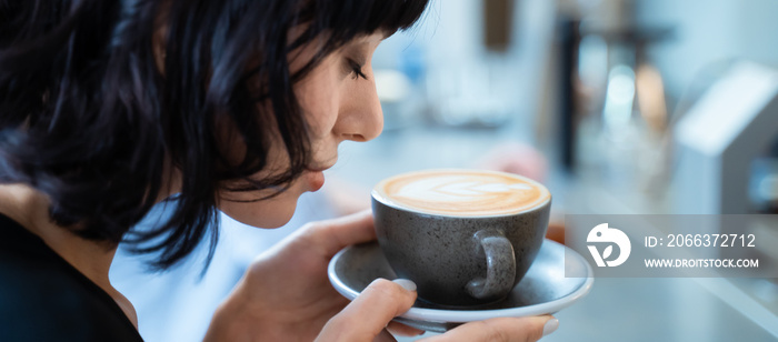 Beautiful customer in cafe restaurant holding cup of latte art coffee