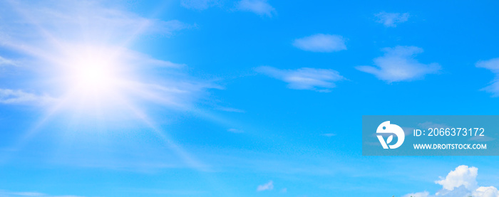 blue summer sky with fluffy clouds and bright sun as a background. Wide photo.