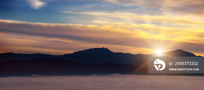 Bright sunrise, the mist in a mountain valley and mountain peaks