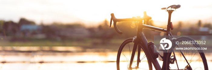 Road bike parked on a beautiful road sunset, warm light with copy space.