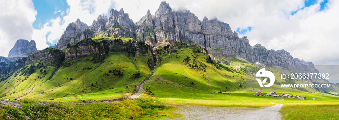 Dramatic panoramic view of a valley in the swiss alps with green meadows and steep rocks at Klausenpass at Canton Uri in Switzerland