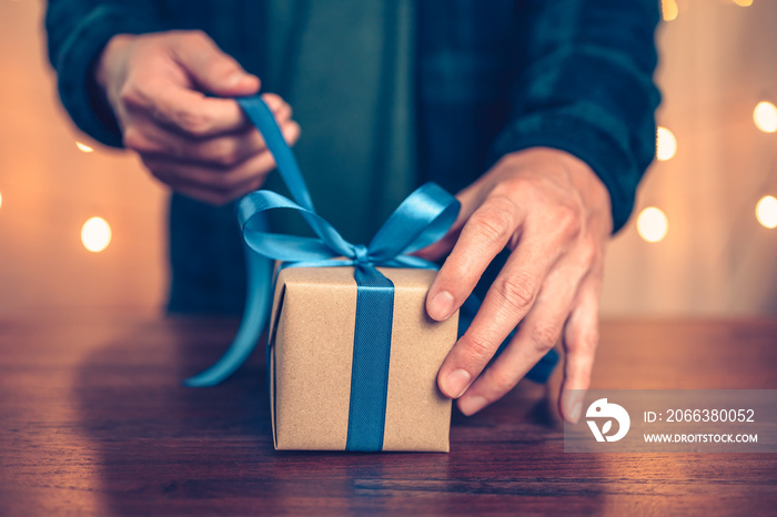 Hands holding gift box, present on the table and light of bokeh background. Valentines Day, Christm