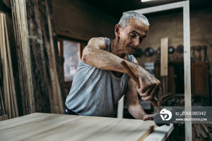 Close up shot of old master carpenter working in his woodwork or workshop. Traditional craftsmanship