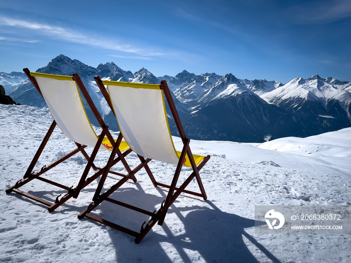 two yellow deck chairs are on the snow