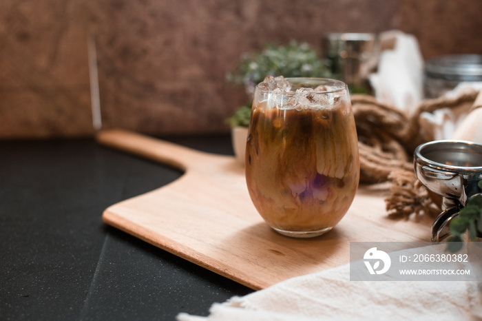 iced coffee in iridescent stemless glass served on black table at cafe​