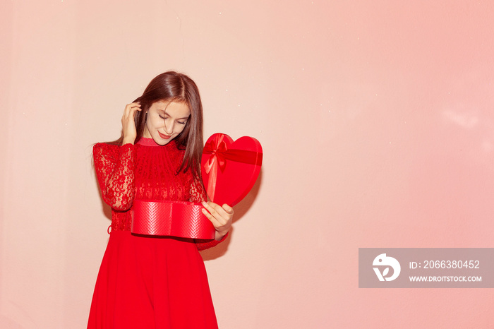 Happy young girl holds heart shaped giftbox. Valentines day, birthday, womens day, anniversary, holi