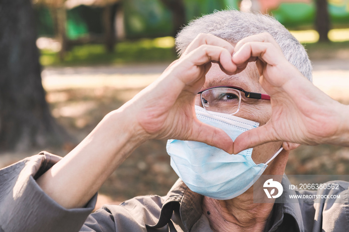 Senior woman making a heart shape, cute and lovely