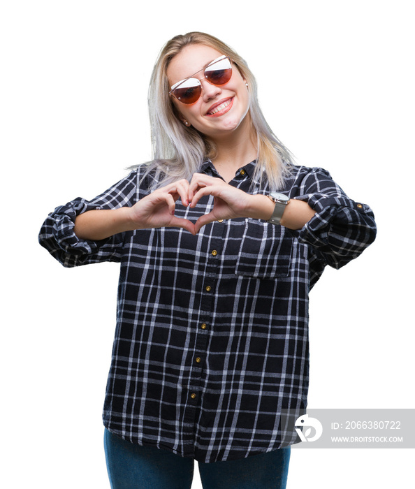 Young blonde woman wearing sunglasses over isolated background smiling in love showing heart symbol 