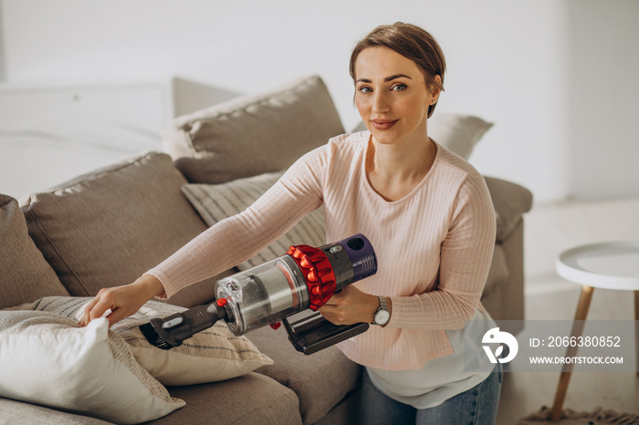 Young woman with rechargeable vacuum cleaner cleaning at home