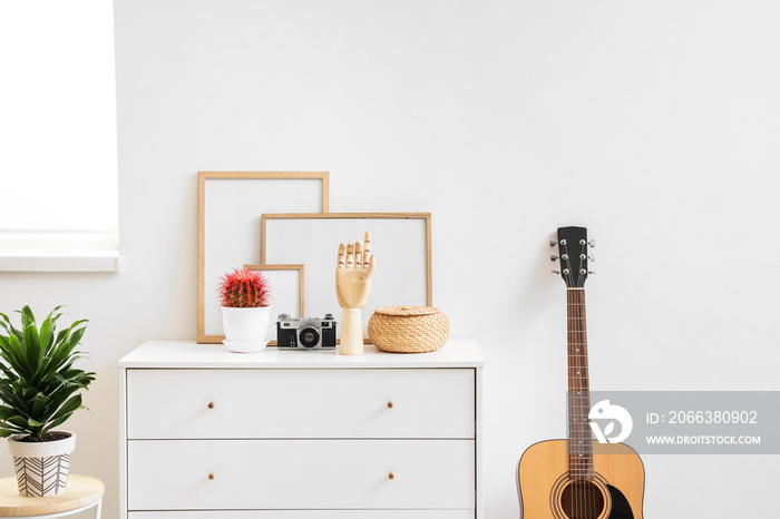 Wooden hand with stylish decor on chest of drawers in interior of room