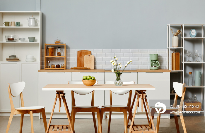 Minimal kitchen interior in white color with wooden accents and dinner table in foreground, copy spa