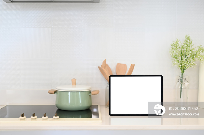 Kitchenware and tablet with white screen on modern kitchen counter.