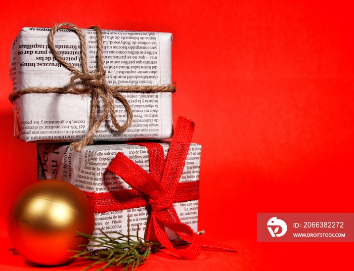 Gifts wrapped in old newspaper on red background