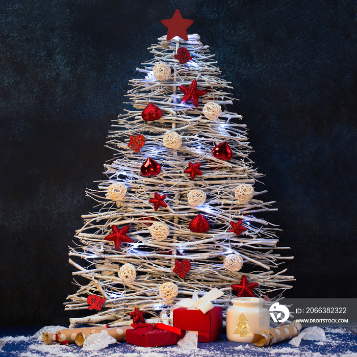White driftwood christmas tree with star and snowflakes decorations on dark blue wooden background