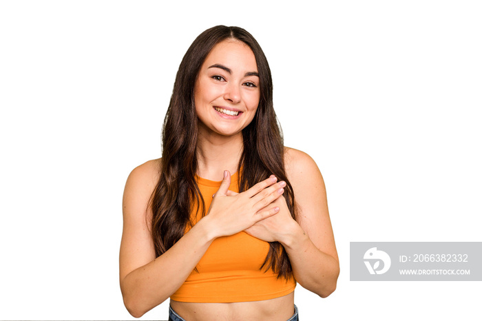 Young caucasian woman isolated on green chroma background has friendly expression, pressing palm to 