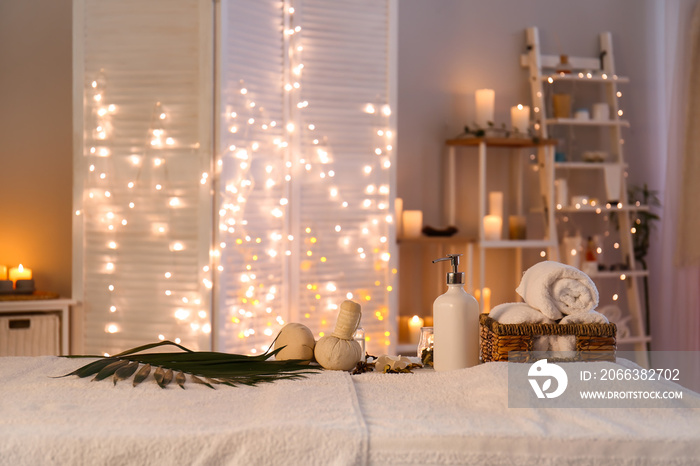 Towels, cosmetics and herbal bags on table in spa salon